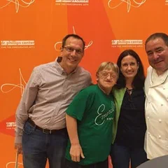 Four people posing at an event with an orange backdrop
