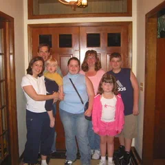 A family group inside a home near wooden doors