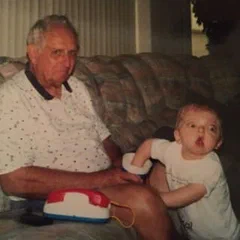 Alex's grandfather and Alex as a toddler in a living room