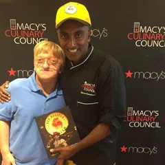 Alex and a family member in front of a Macy's backdrop