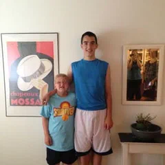 Alex and a friend standing side by side in a room with framed posters