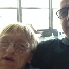 Alex and a friend sitting close together, smiling