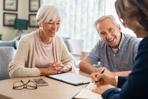 An older couple reviewing documents with an advisor at a table