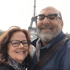 Alan Farah and his wife smiling with the Eiffel Tower behind them