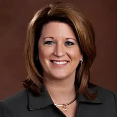 Colleen Schon, a professional woman with shoulder-length hair, smiling against a brown background